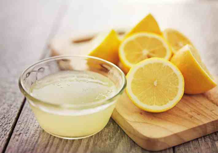 A closeup photograph of fresh squeezed lemon juice in a glass bowl